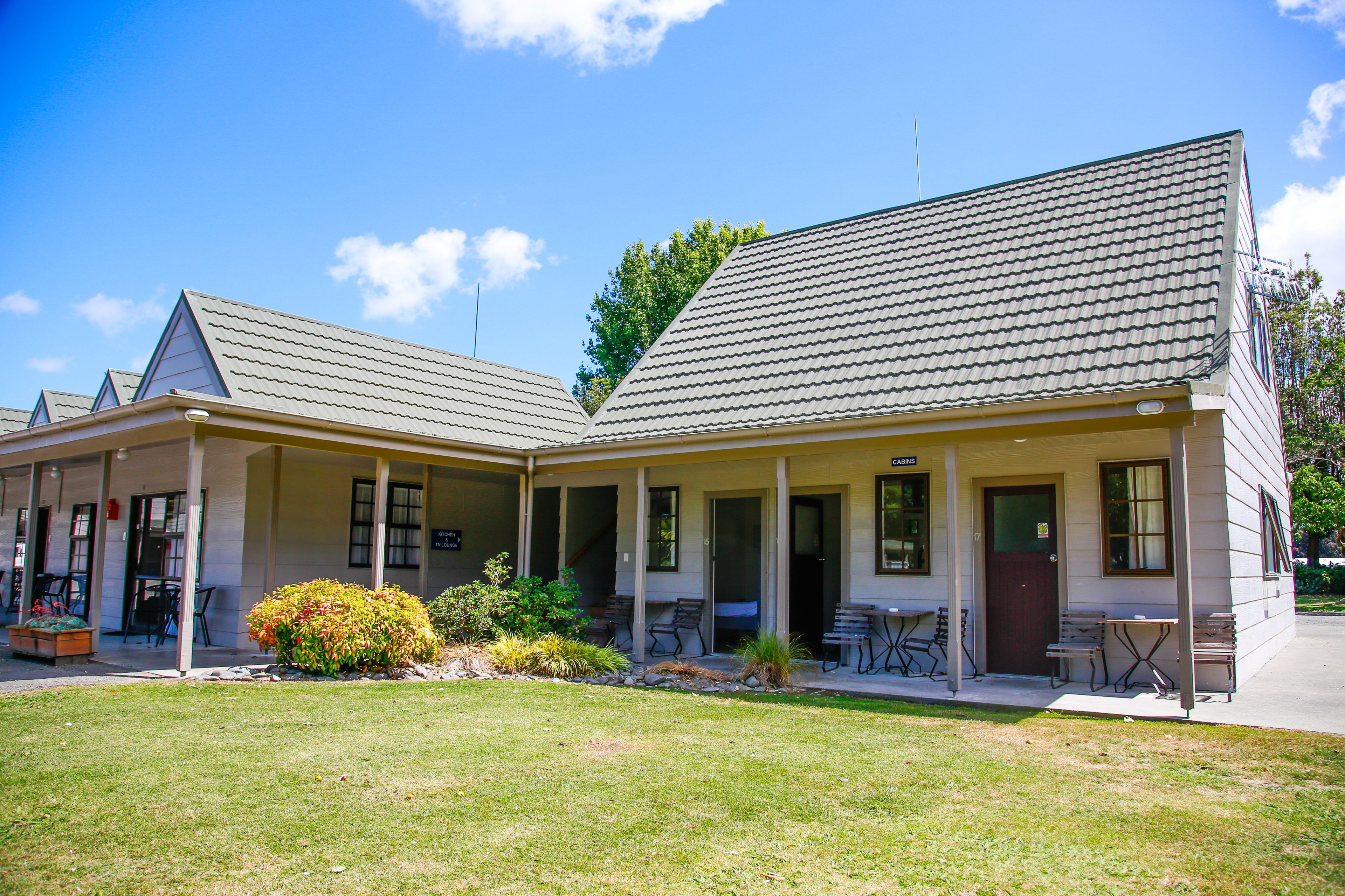 A two-story building with a covered patio area, outdoor seating, and a small garden.