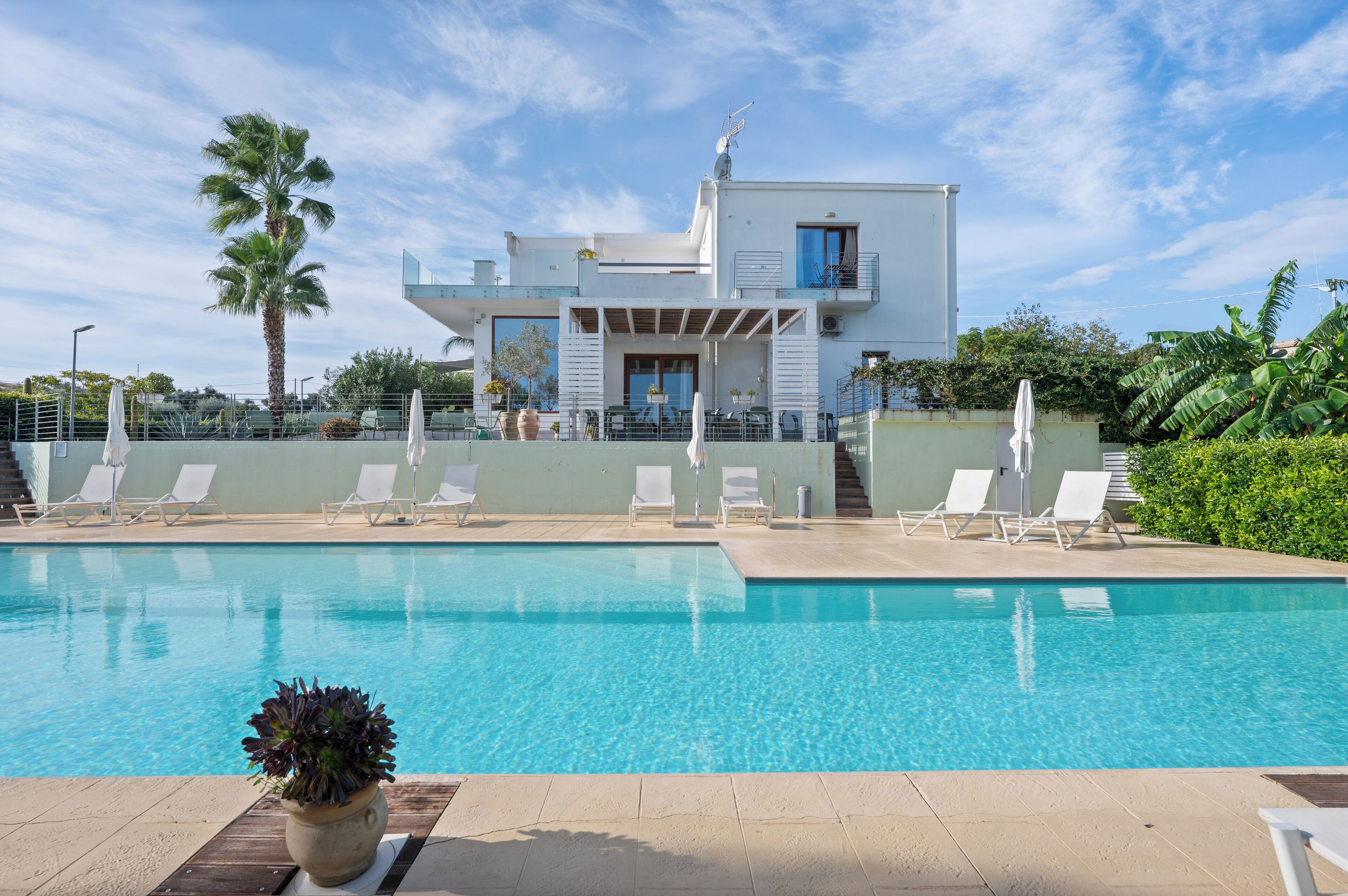 Un edificio moderno con piscina y sillones de descanso.