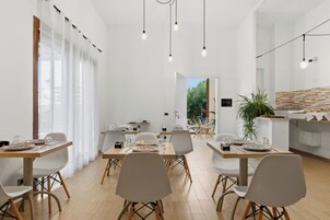 Un comedor moderno con sillas blancas, mesas de madera e iluminación colgante.