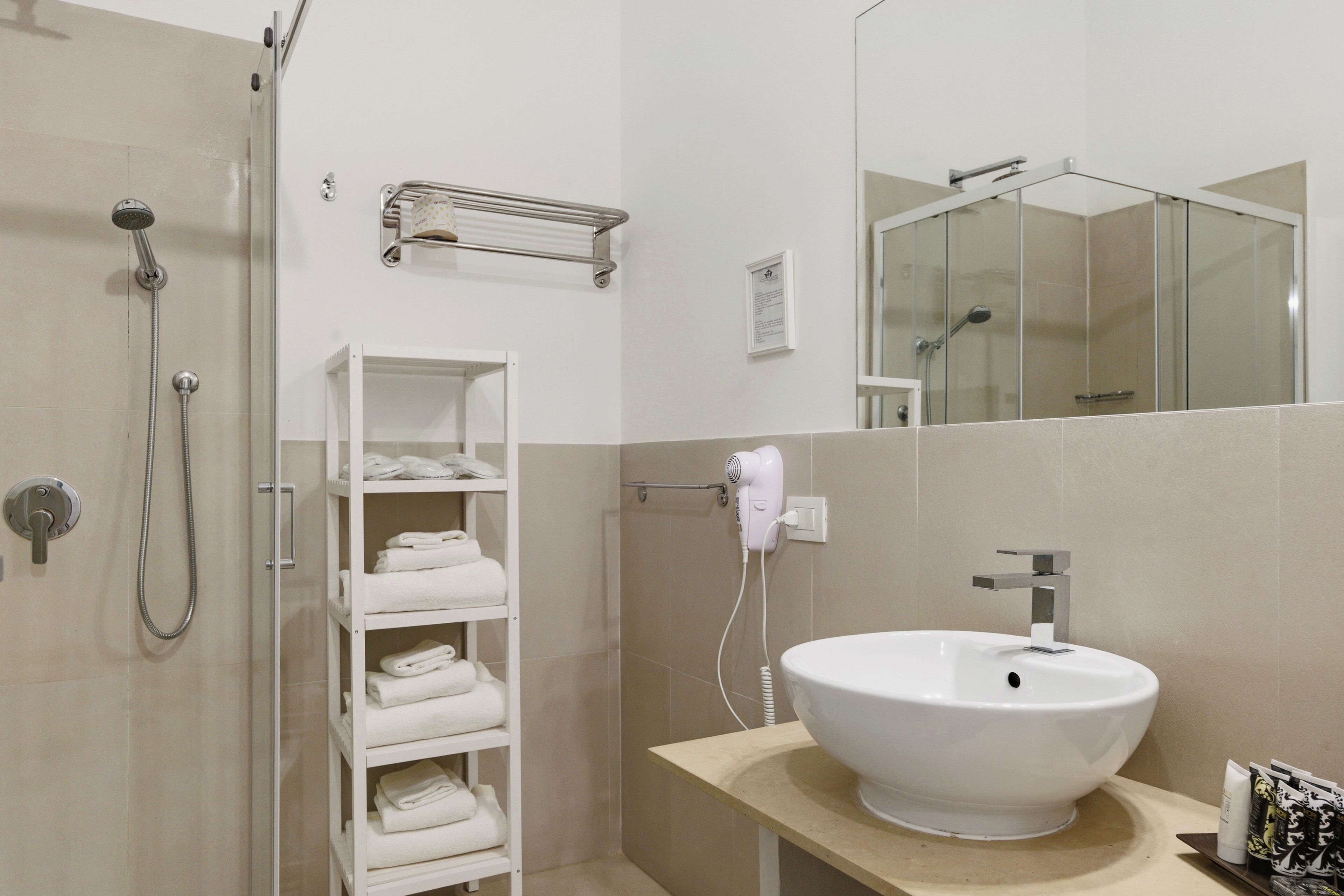 Une salle de bain moderne avec une douche à parois de verre, un lavabo blanc et un porte-serviettes.