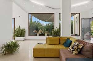 Una sala de estar moderna con un sofá amarillo, un sofá marrón y un ventanal de vidrio que da a un balcón.