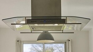 Une cuisine moderne dotée d’un grand îlot central, d’un four encastré et d’une fenêtre offrant une vue sur l’extérieur.