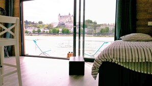 A room with a large window offering a view of a historic castle across a river.