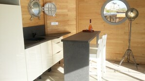 A modern kitchen with wooden walls, a central island, a round window, and a floor lamp.