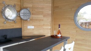 A modern kitchen with a wooden wall, a round window, a black countertop, and a white chair.