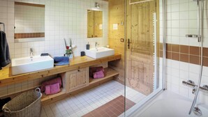 A modern bathroom with two sinks, a glass shower enclosure, and wooden cabinetry.
