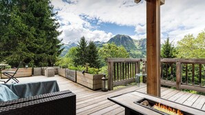 A wooden deck with outdoor furniture, a fire pit, and a view of mountains.