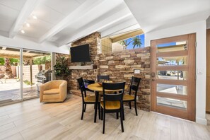 A modern outdoor dining area with a stone wall, a flat-screen TV, and a sliding glass door leading to a patio. - El Paseo, 'The Rodeo Drive of Beverly Hills' In Palm Desert. Free  Wi FI (Palm Desert)