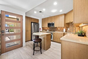 A modern kitchen with wooden cabinets, stainless steel appliances, and a central island with stools. - El Paseo, 'The Rodeo Drive of Beverly Hills' In Palm Desert. Free  Wi FI (Palm Desert)