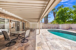 A covered patio area with a pool, stone flooring, and outdoor furniture. - El Paseo, 'The Rodeo Drive of Beverly Hills' In Palm Desert. Free  Wi FI (Palm Desert)