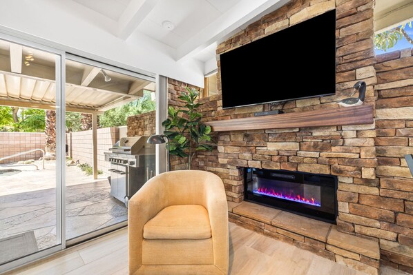 A modern living room with a stone fireplace, a flat-screen TV mounted above it, and a grill outside. - El Paseo, 'The Rodeo Drive of Beverly Hills' In Palm Desert. Free Wi FI (Palm Desert)