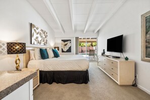 Une chambre à coucher comprenant un lit, une télévision, une commode et des œuvres d’art accrochées aux murs.