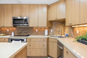 A modern kitchen with wooden cabinets, stainless steel appliances, and a brick backsplash. - El Paseo, 'The Rodeo Drive of Beverly Hills' In Palm Desert. Free Wi FI (Palm Desert)