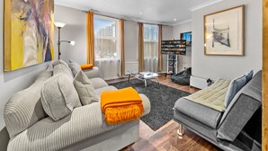 Un salon moderne avec un canapé, un divan gris, une table basse et une bibliothèque.