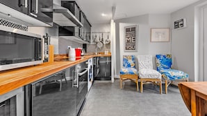 Une cuisine moderne dotée d’appareils électroménagers en acier inoxydable, d’un plan de travail en bois et d’un coin repas avec des chaises en osier.