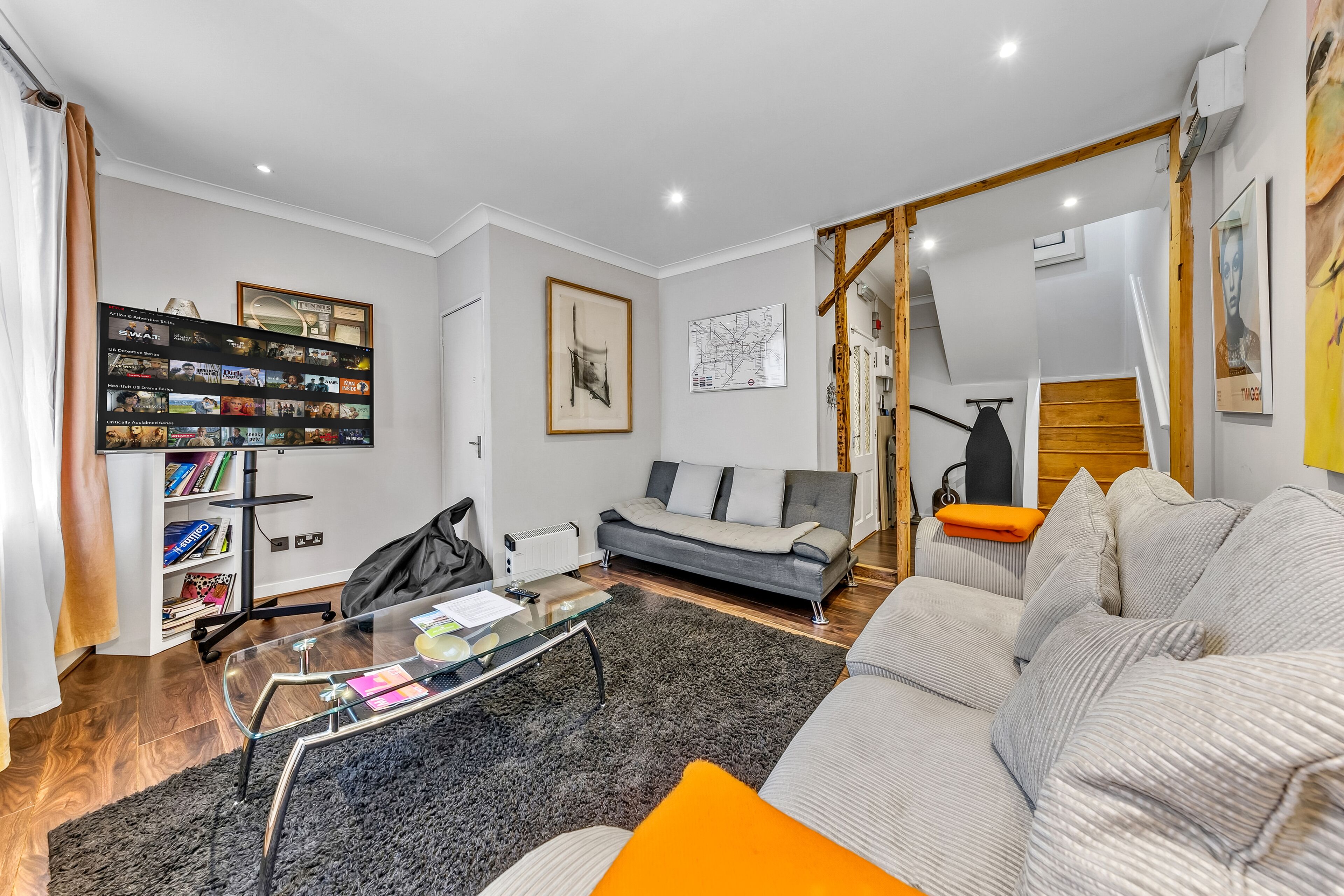 A modern living room with a sofa, a glass coffee table, and a bookshelf.