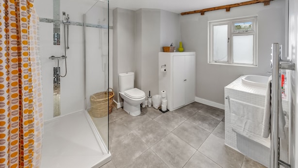 Une salle de bain avec une douche à parois de verre, des toilettes, un lavabo et une fenêtre.