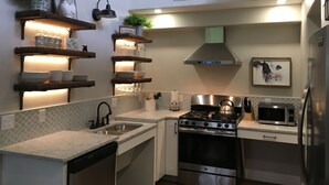 Une cuisine moderne dotée d’appareils électroménagers intégrés, d’étagères en bois et d’une enseigne de style rustique.