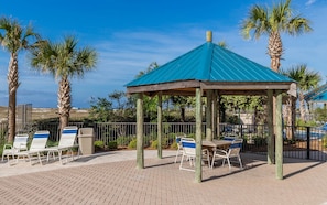 Relax in a serene gazebo-style seating area surrounded by palm trees and a pool view.