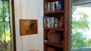 A cozy reading nook with a wooden bookshelf, a framed picture, a lamp, and a striped cushion.