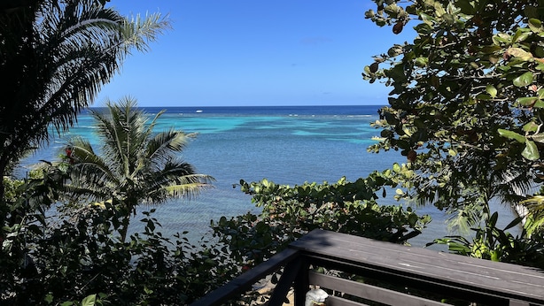 A view of the ocean from a covered area with a wooden deck.