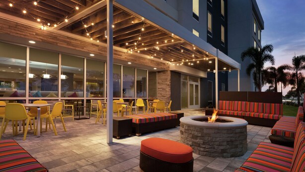 An outdoor seating area with yellow chairs, a fire pit, and striped cushions. - Home2 Suites by Hilton Sarasota - Bradenton Airport, FL (Sarasota)