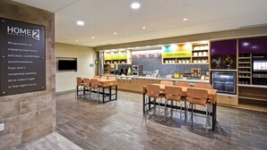 A modern hotel lobby with a reception area, seating, and a kitchen counter.