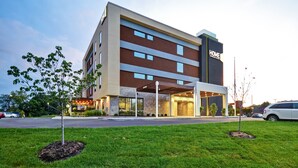 A modern hotel with a flat roof, multiple floors, and a prominent "HOME" sign.