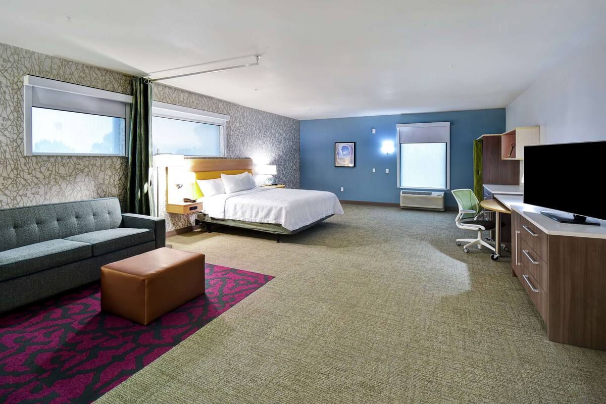 Una habitación de hotel con cama, sofá, escritorio y televisor.
