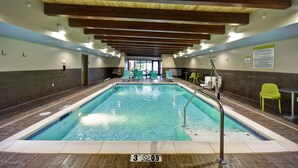 An indoor swimming pool with a wooden ceiling, clear water, and a no diving sign.