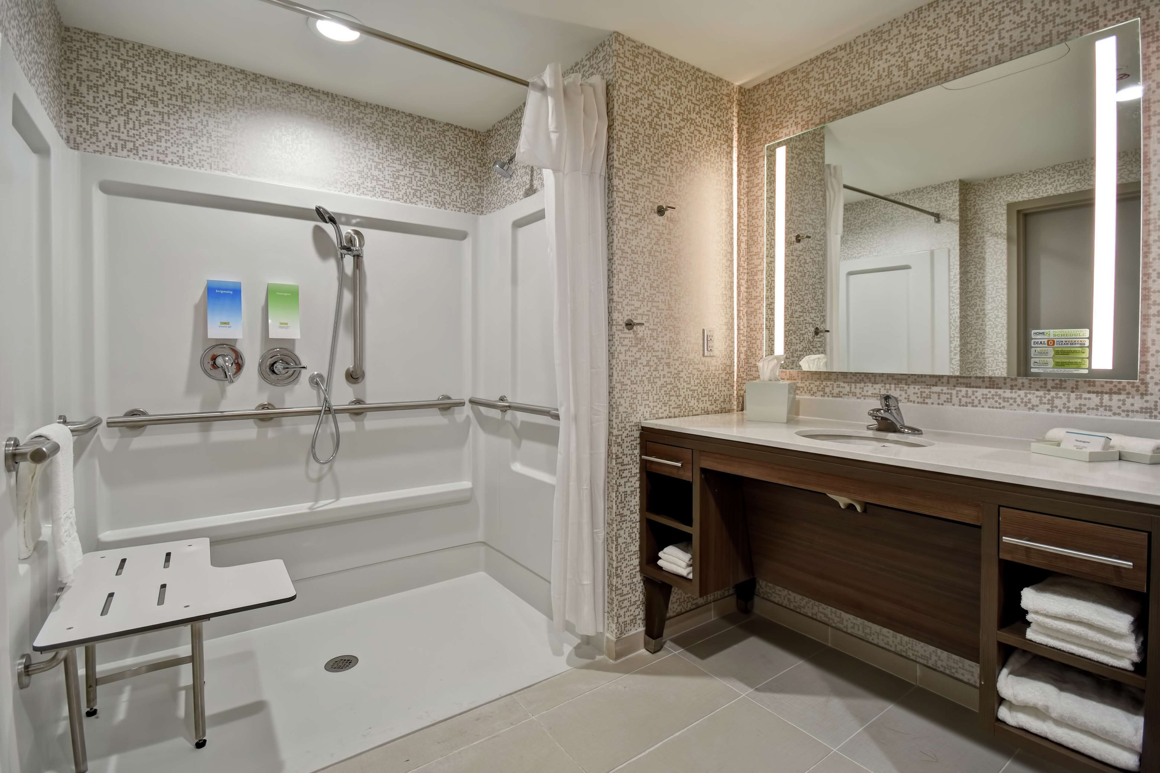 A modern bathroom with a walk-in shower, a vanity with a mirror, and a towel rack.