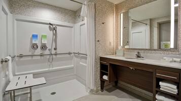 A modern bathroom with a walk-in shower, a vanity with a mirror, and a towel rack.