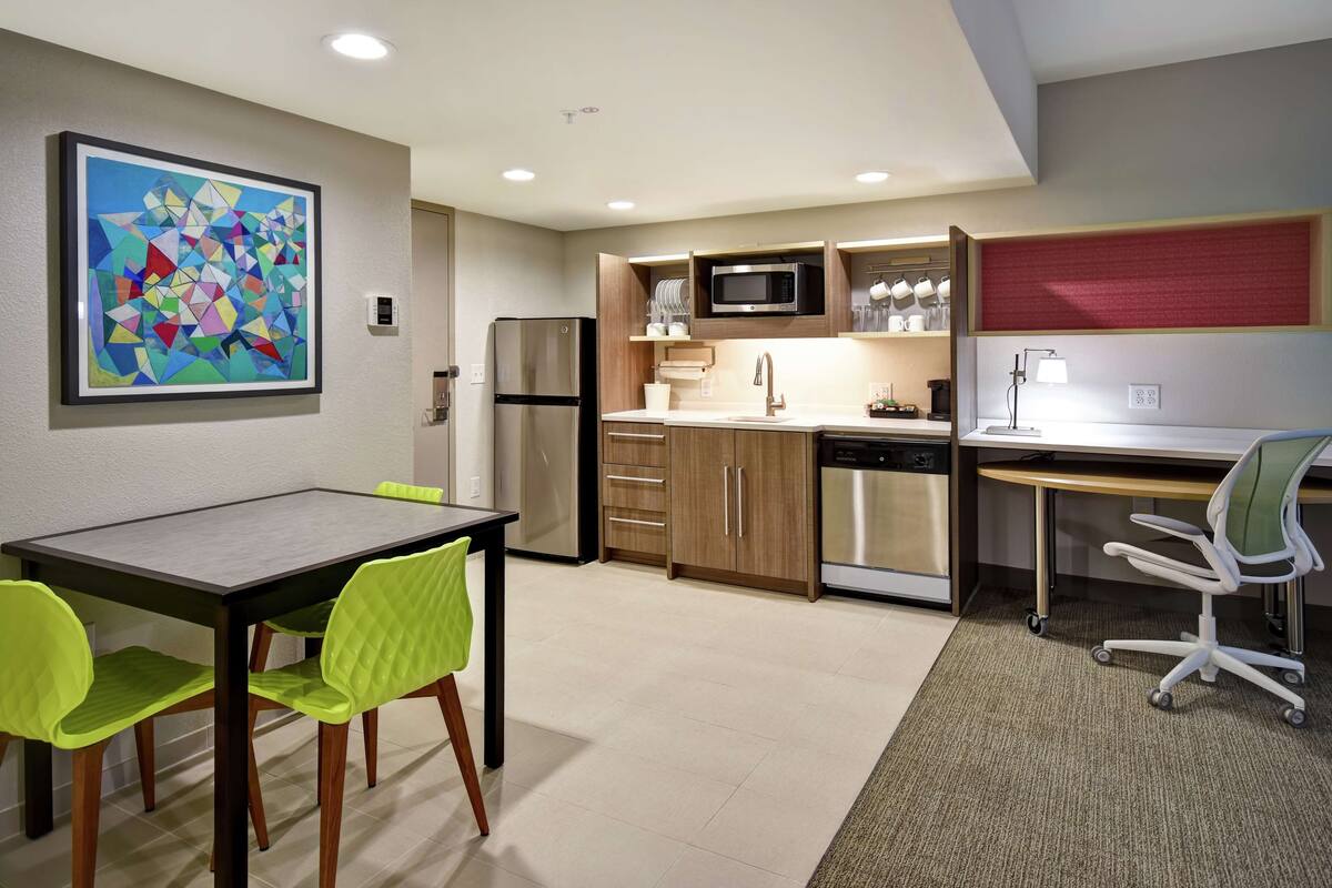 Una cocina moderna con comedor, que incluye una mesa, sillas y un microondas.