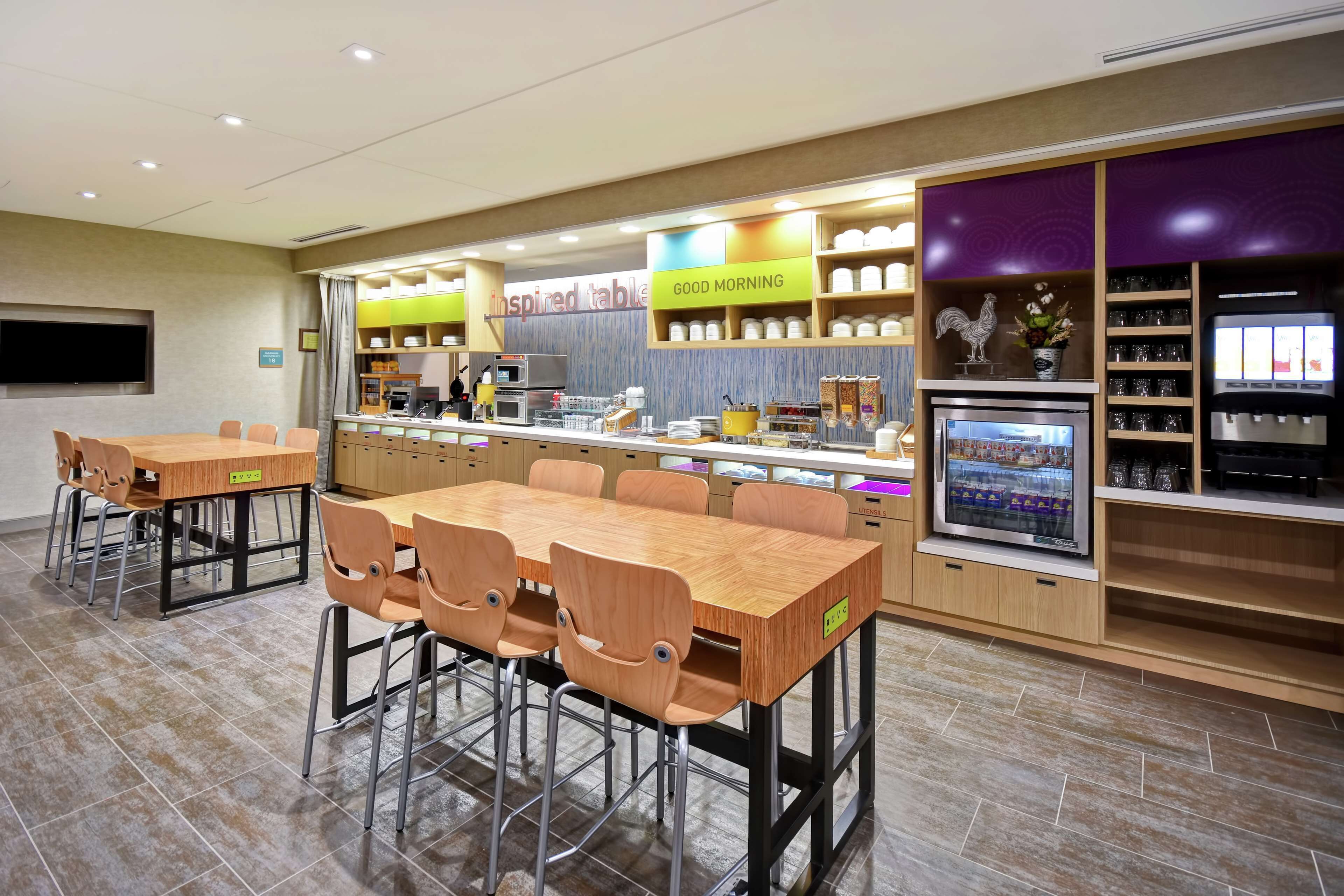 A modern restaurant with a long counter, multiple seating areas, and a variety of food and drink displays.