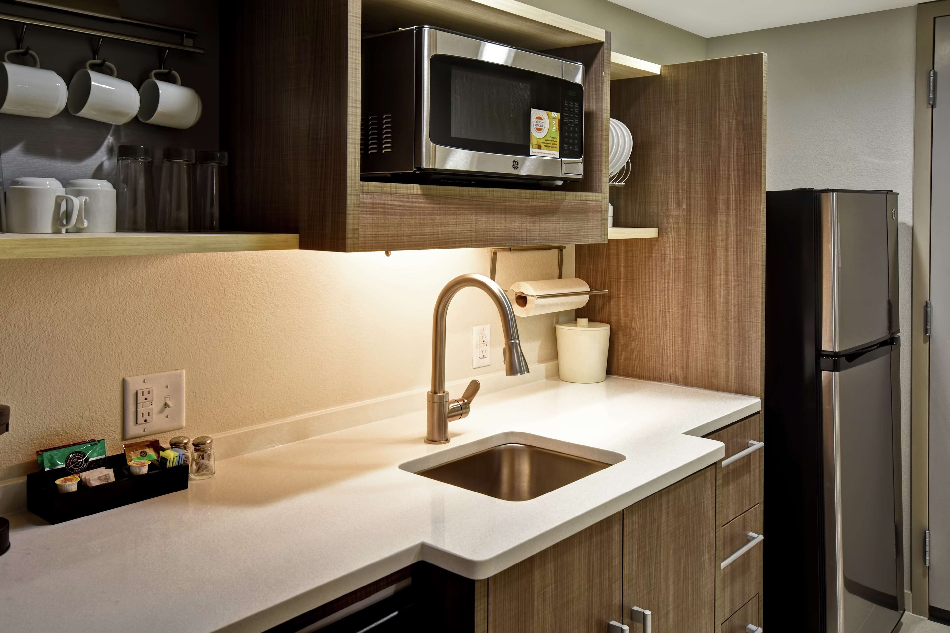 Una cocina moderna con un microondas de acero inoxidable, un lavaplatos y un refrigerador.