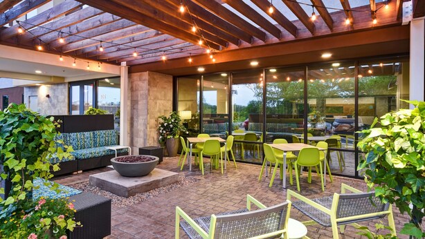 An outdoor patio with seating, a fire pit, and a pergola with string lights.