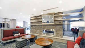 Ein moderner Loungebereich mit Kamin aus Stein, Sofas und runden Tischen.