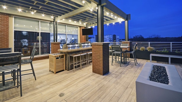 Ein Außenbereich mit Terrasse, Bar, Sitzgelegenheiten und einem Fernsehbildschirm.