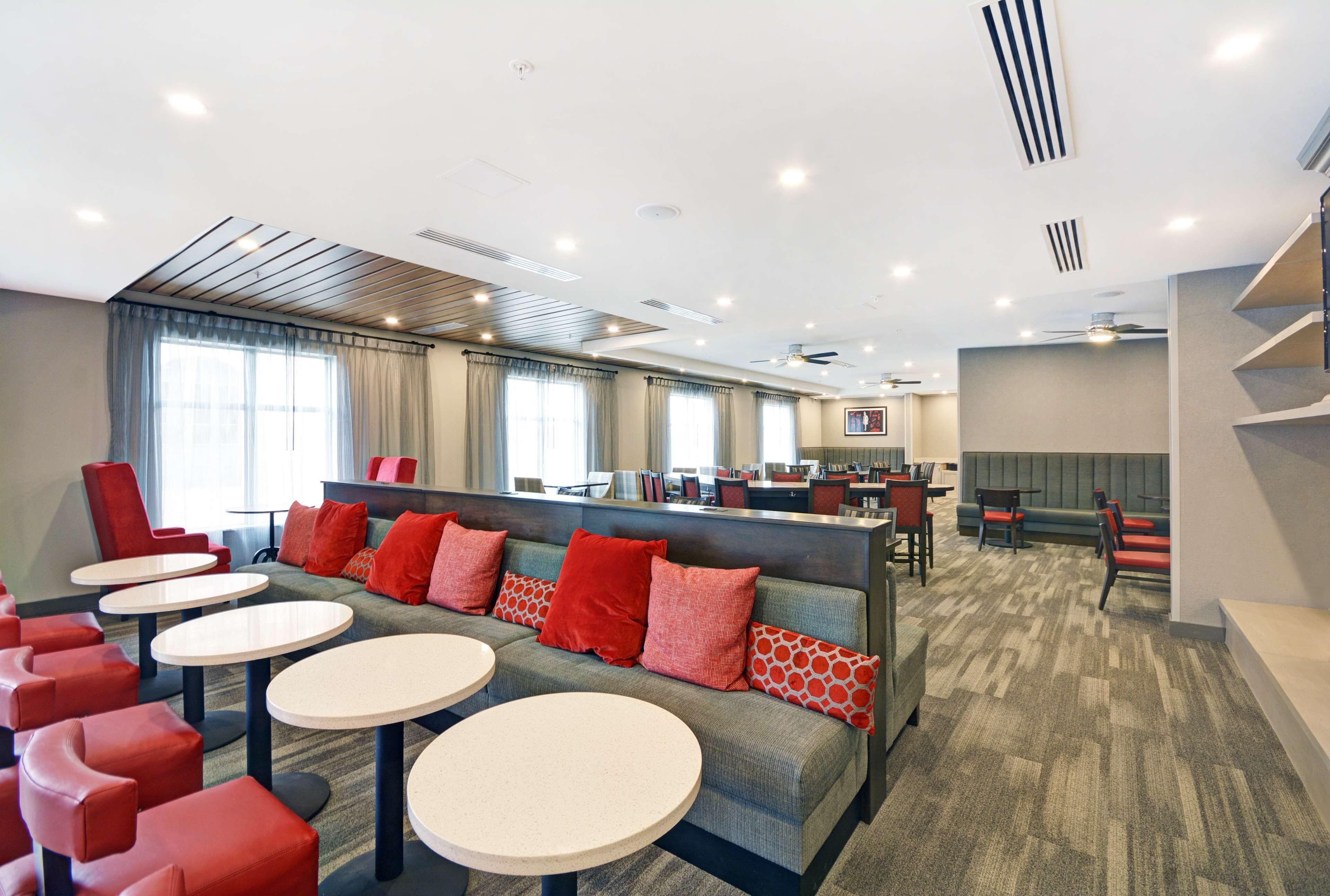 A modern hotel lobby with a seating area, round tables, and a reception desk.