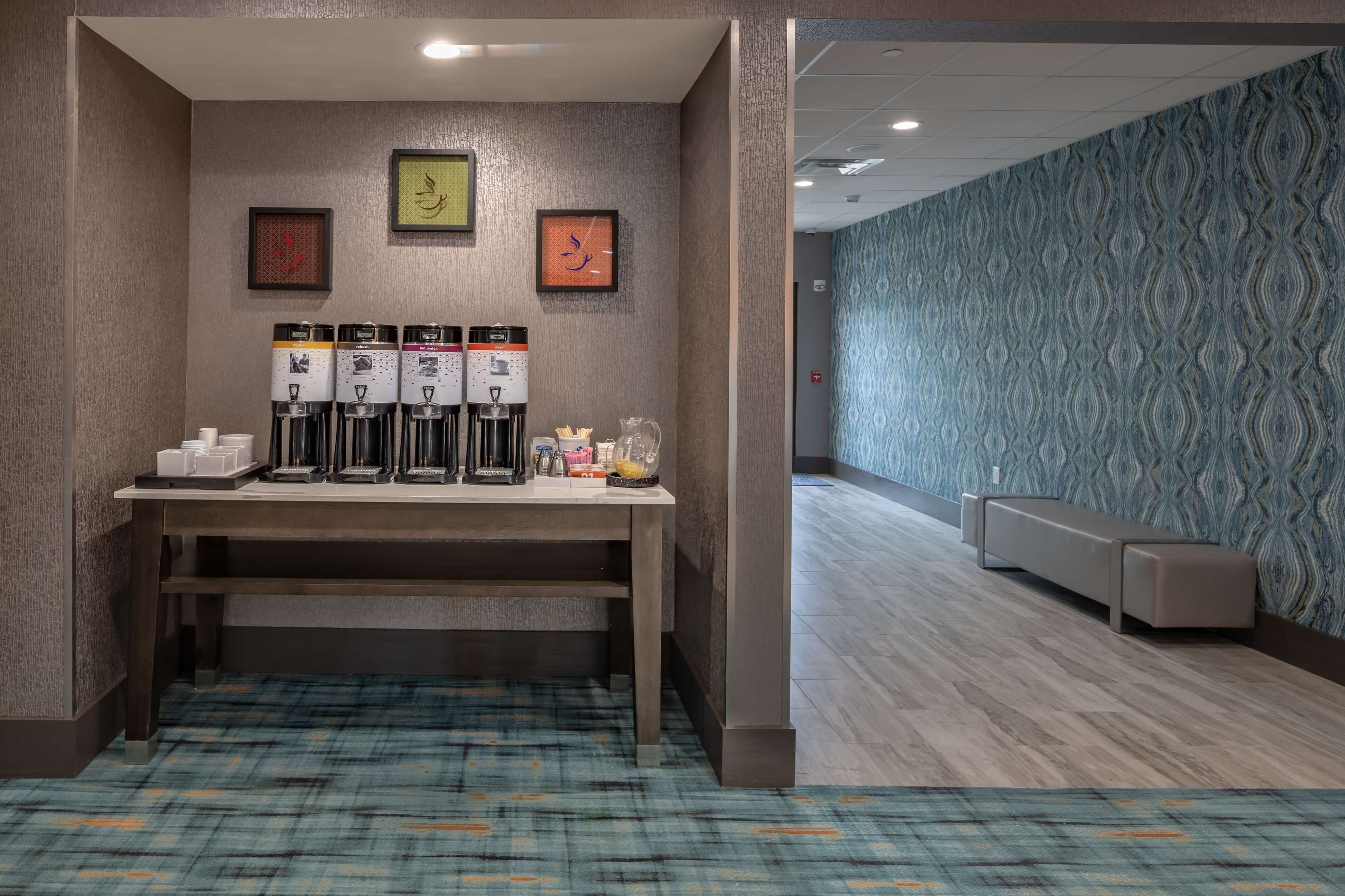 Un hall d'hôtel avec un coin café, un espace salon et un papier peint à motifs.