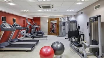 Un gimnasio con cintas de correr, elípticas, máquinas de pesas y pelotas de ejercicio.