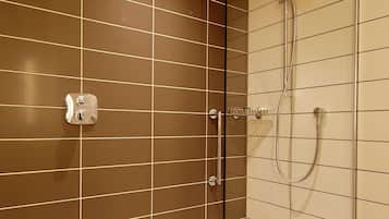 Et moderne badeværelse med en glasafskærmet brusekabine, et hvidt badekar og et panel til betjening på væggen.