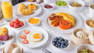 A breakfast spread with various dishes including eggs, sausages, tomatoes, and fruits.