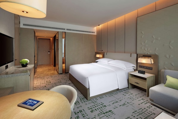A hotel room with a bed, bedside tables, a desk, a chair, and a TV.