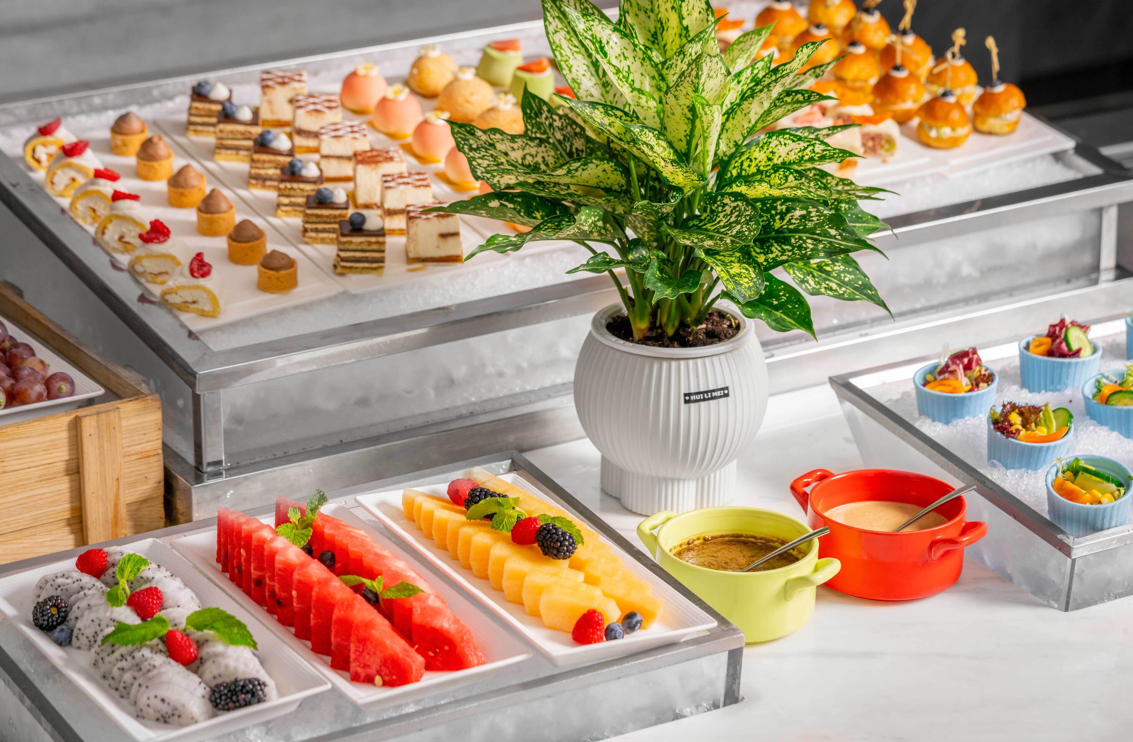 A buffet with various desserts and fruits, including watermelon, strawberries, and blueberries.