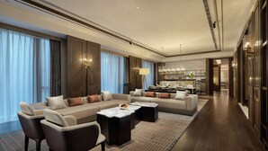 A spacious living area with a sectional sofa, two armchairs, and a coffee table. There is a kitchen area visible in the background with modern appliances and a dining area. - Hilton Chengdu Chenghua - Close to Panda Base and Chengdu East Railway Station (Chengdu)
