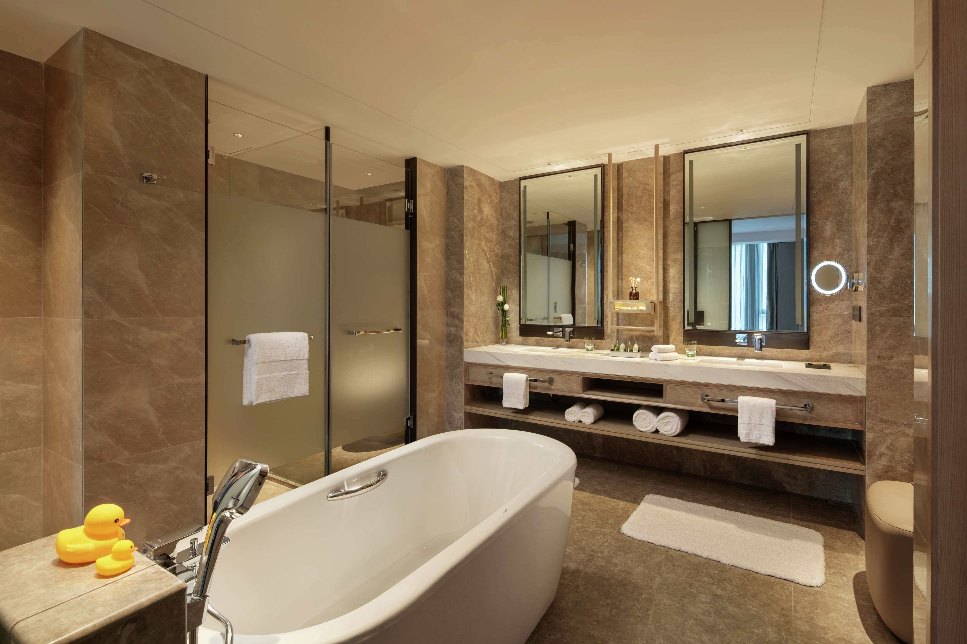 Une salle de bain moderne avec une baignoire sur pieds, une douche à parois de verre et un meuble-lavabo doté d’un grand miroir.
