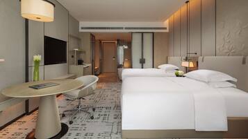 A modern hotel room with a large bed, a desk, and a flat-screen TV.