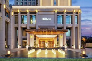 A modern hotel entrance with a large illuminated sign, a covered entrance, and a water feature in front. - Hilton Chengdu Chenghua - Close to Panda Base and Chengdu East Railway Station (Chengdu)