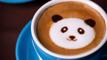 Una taza de café con un diseño de arte latte que representa el rostro de un panda.